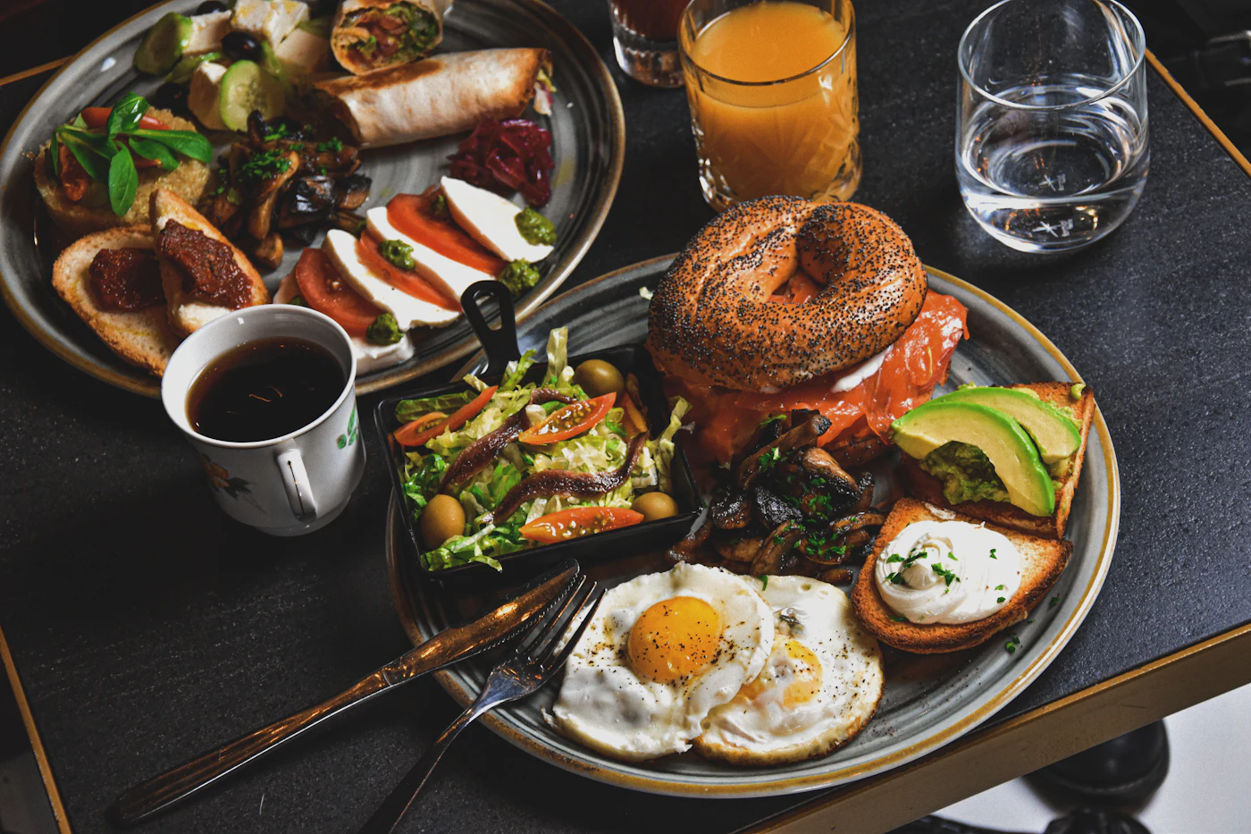 Mesa servida con varios platos de brunch: tostadas, huevos, frutas y café, vista desde arriba