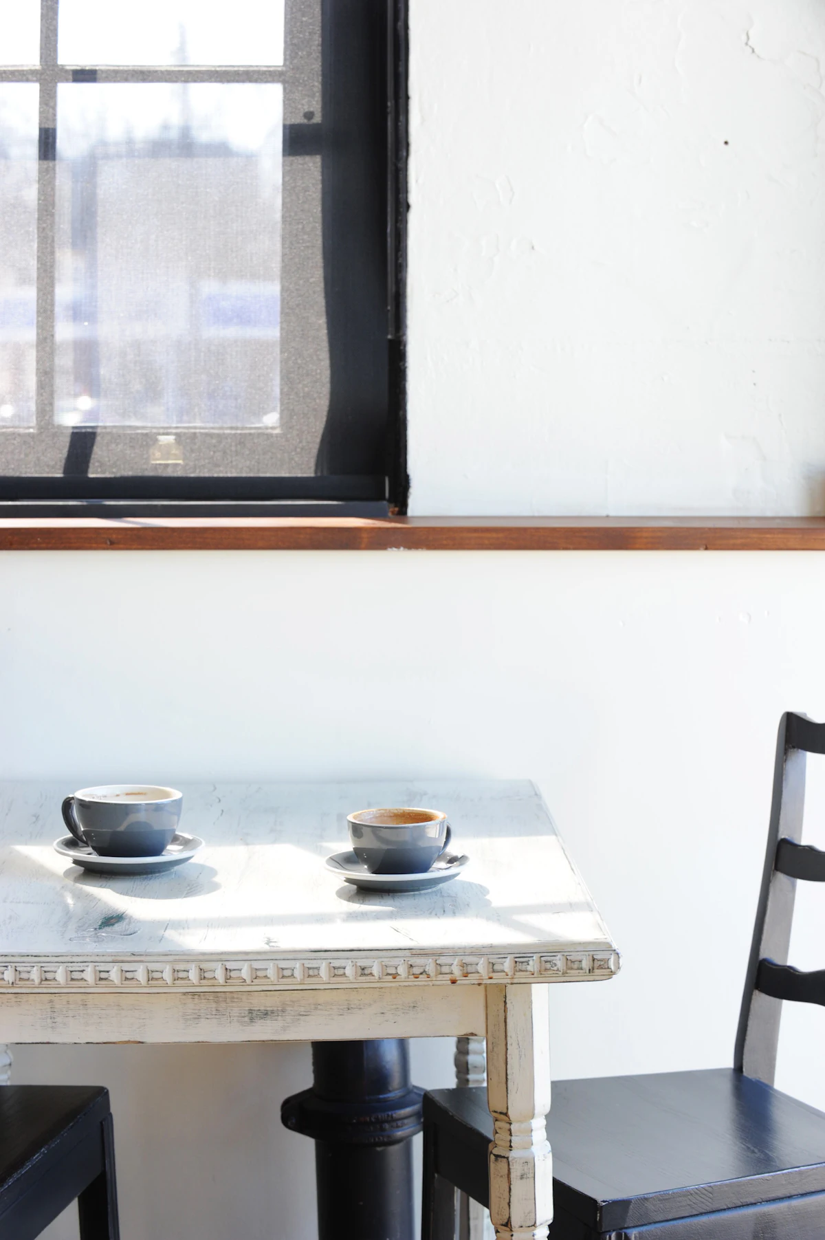 Mesa junto a la ventana con un café y un cuaderno abierto, iluminada por la luz de la mañana